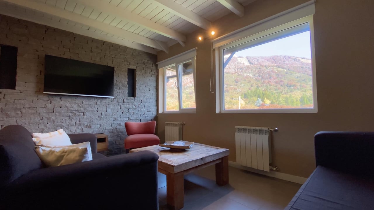 Living room with a stone television wall and mountain views through large windows.