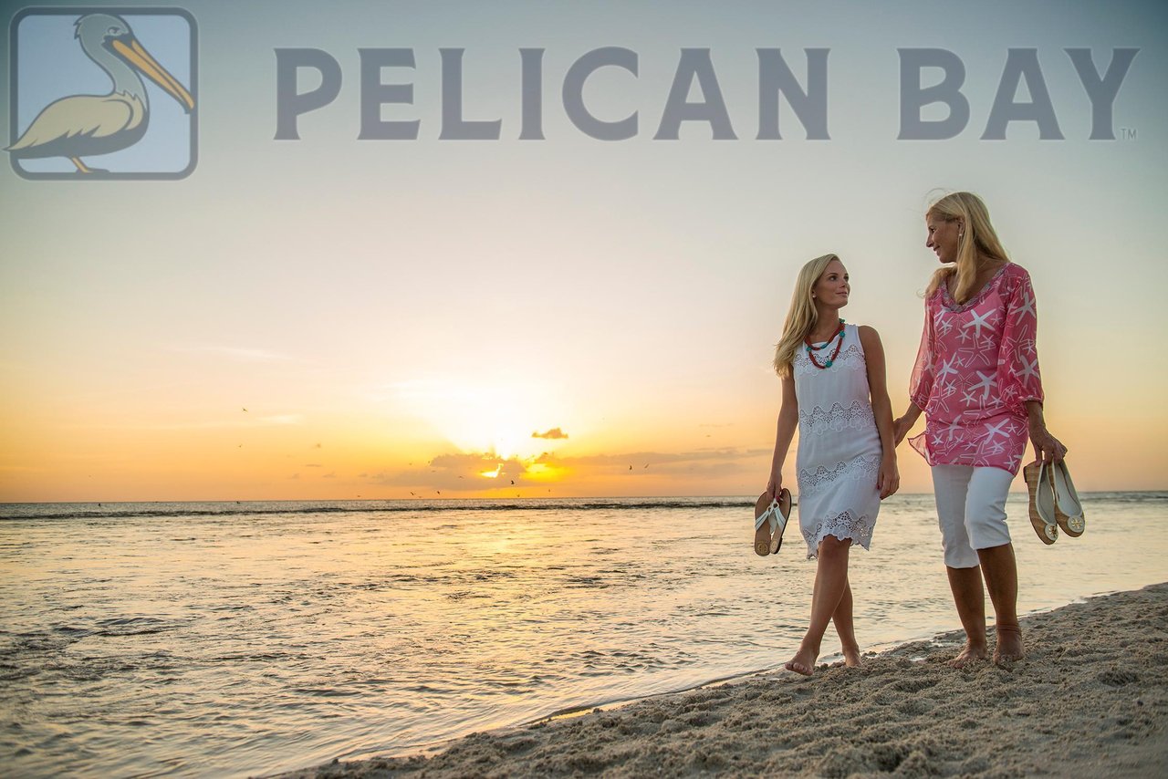 Two women walking barefoot at sunset along the private Pelican Bay beach in Naples Florida