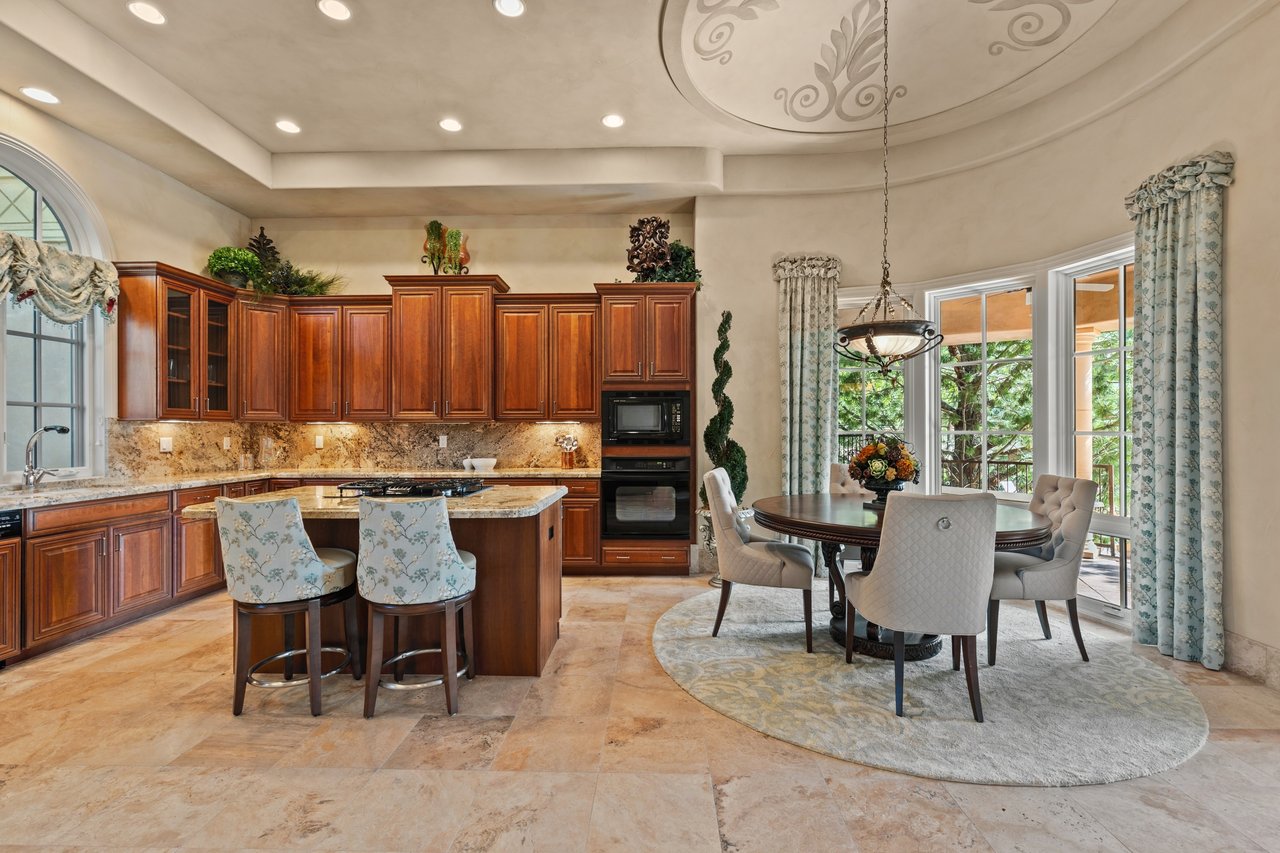 Guest house kitchen and dining area with a wood island and round table beside tall windows.