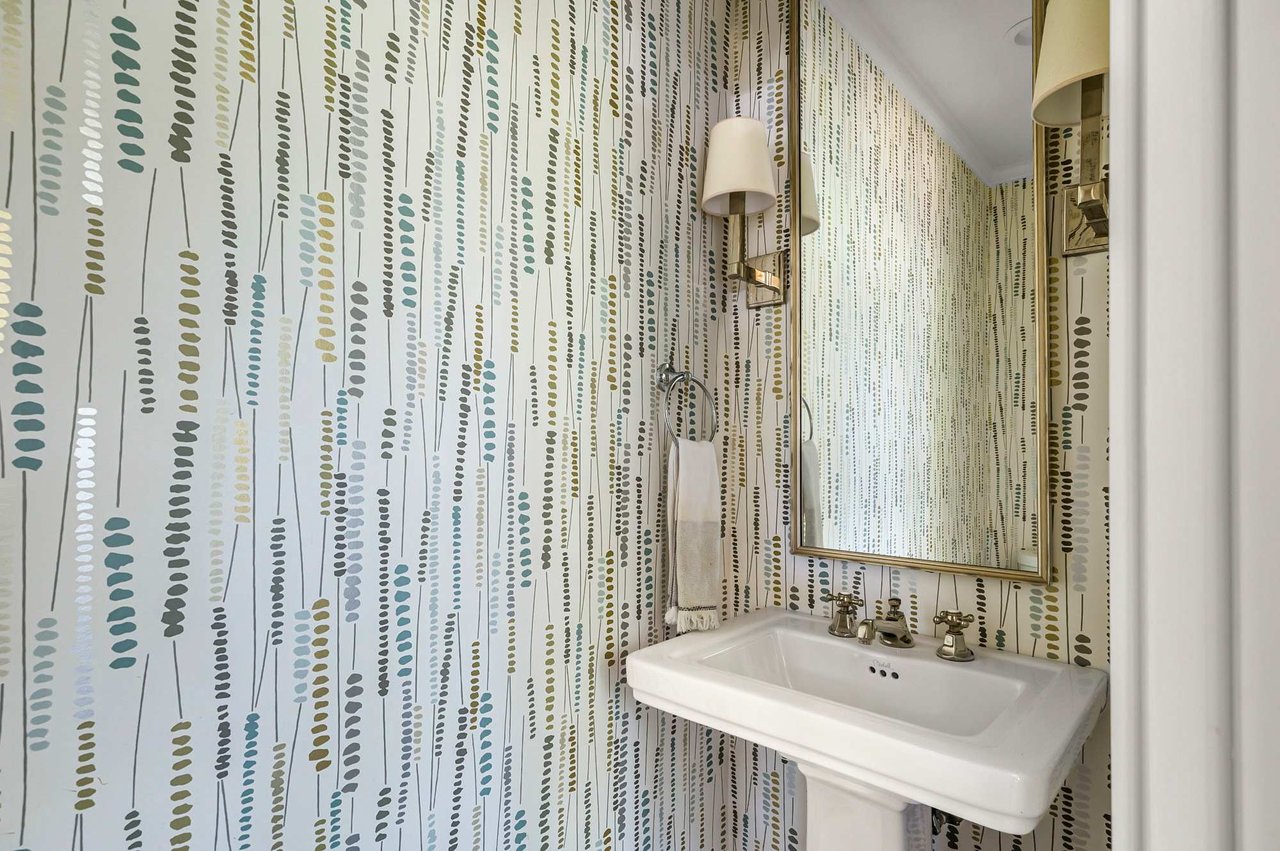 Bathroom with patterned wallpaper and pedestal sink at 1500 Northwood Rd, Pemberton Heights, Austin.