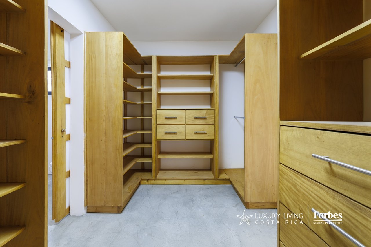 Walk-in closet with extensive light wood built-in shelves and drawers.