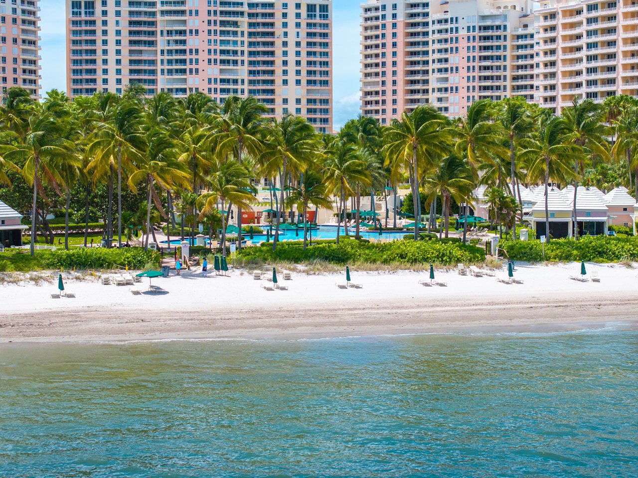 The Ocean Club beachfront with palm trees, resort towers, a pool, and white sand.