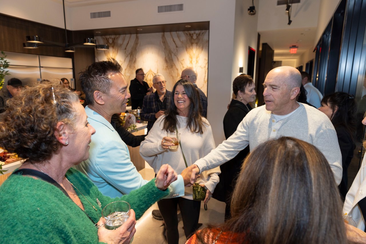Guests mingle at an open house, chatting over drinks in a modern interior.