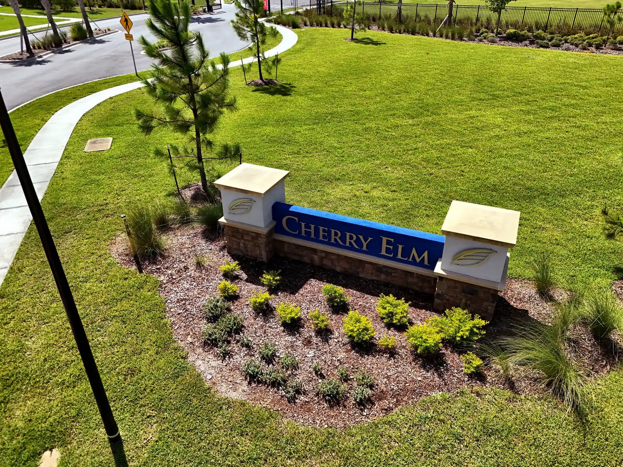 Cherry Elm community entrance sign amid landscaped lawn and a curved sidewalk.