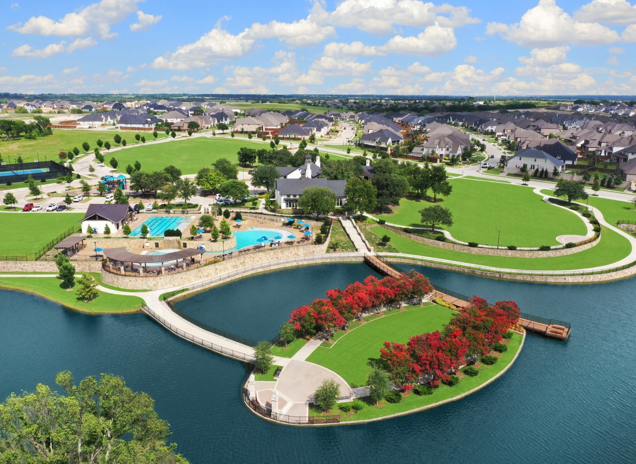 Aerial view of Mustang Lakes in Celina TX showcasing the stunning 115-acre lake, resort-style pool complex, island park, and luxury homes in this premier North DFW master-planned community.
