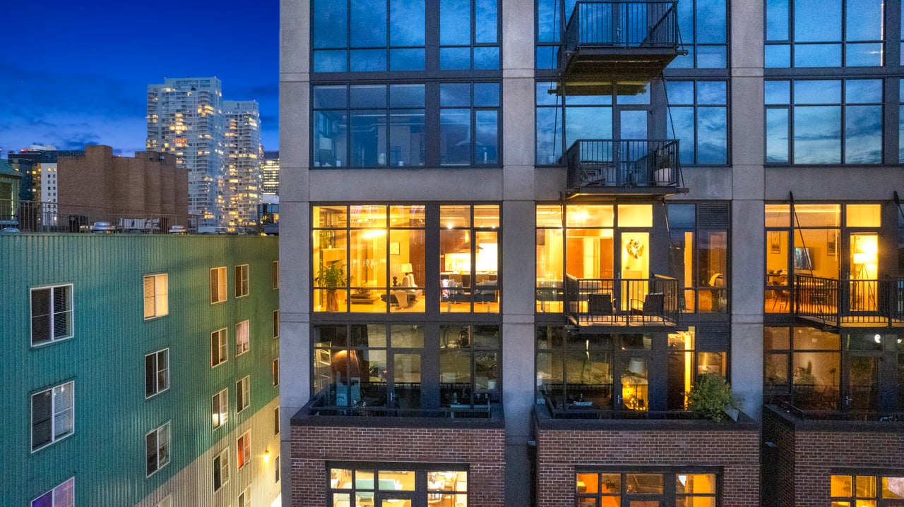  A multi-story residential building, likely a loft or condo, at dusk. 