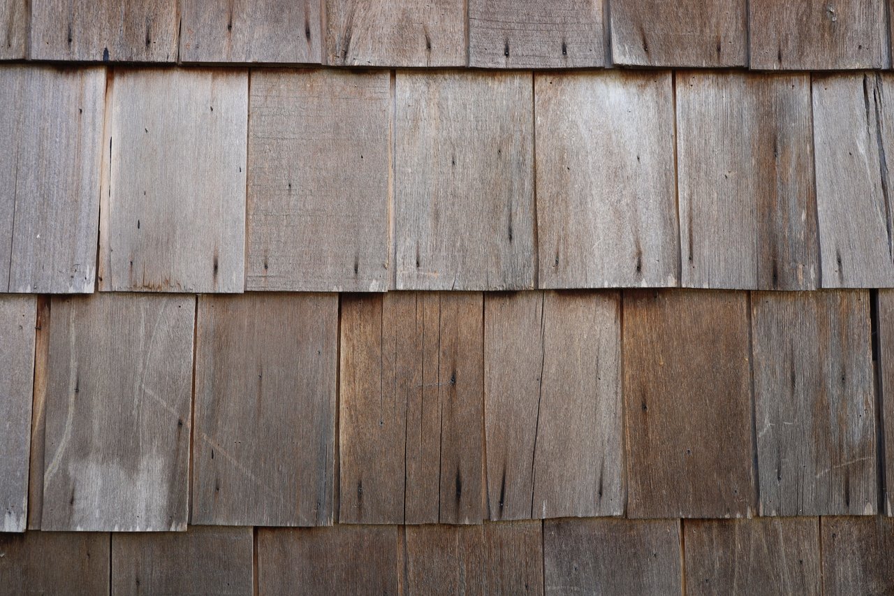 Weathered gray-brown wooden shingles with visible grain and knots.