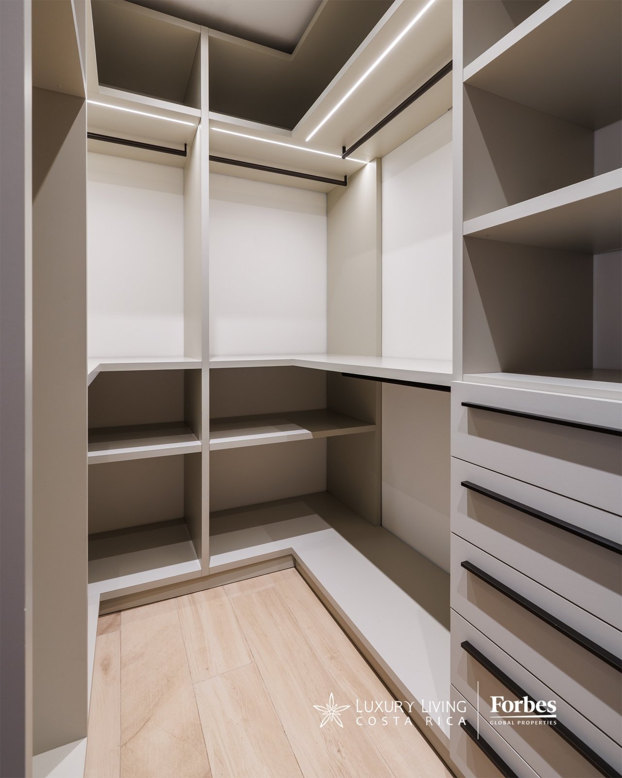 Walk-in closet with built-in shelving, drawers, hanging rails, and integrated lighting.