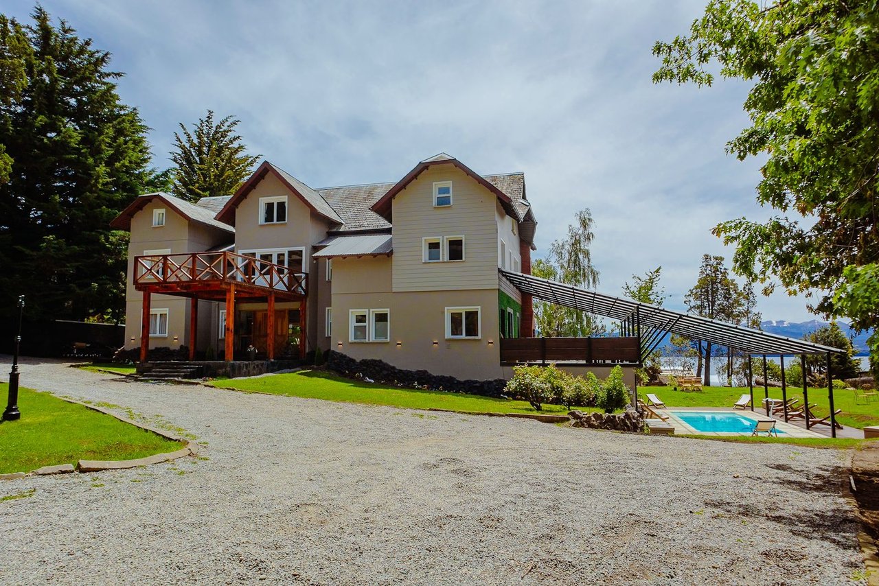 Boutique hotel with a timber balcony and covered pool terrace beside a lake.