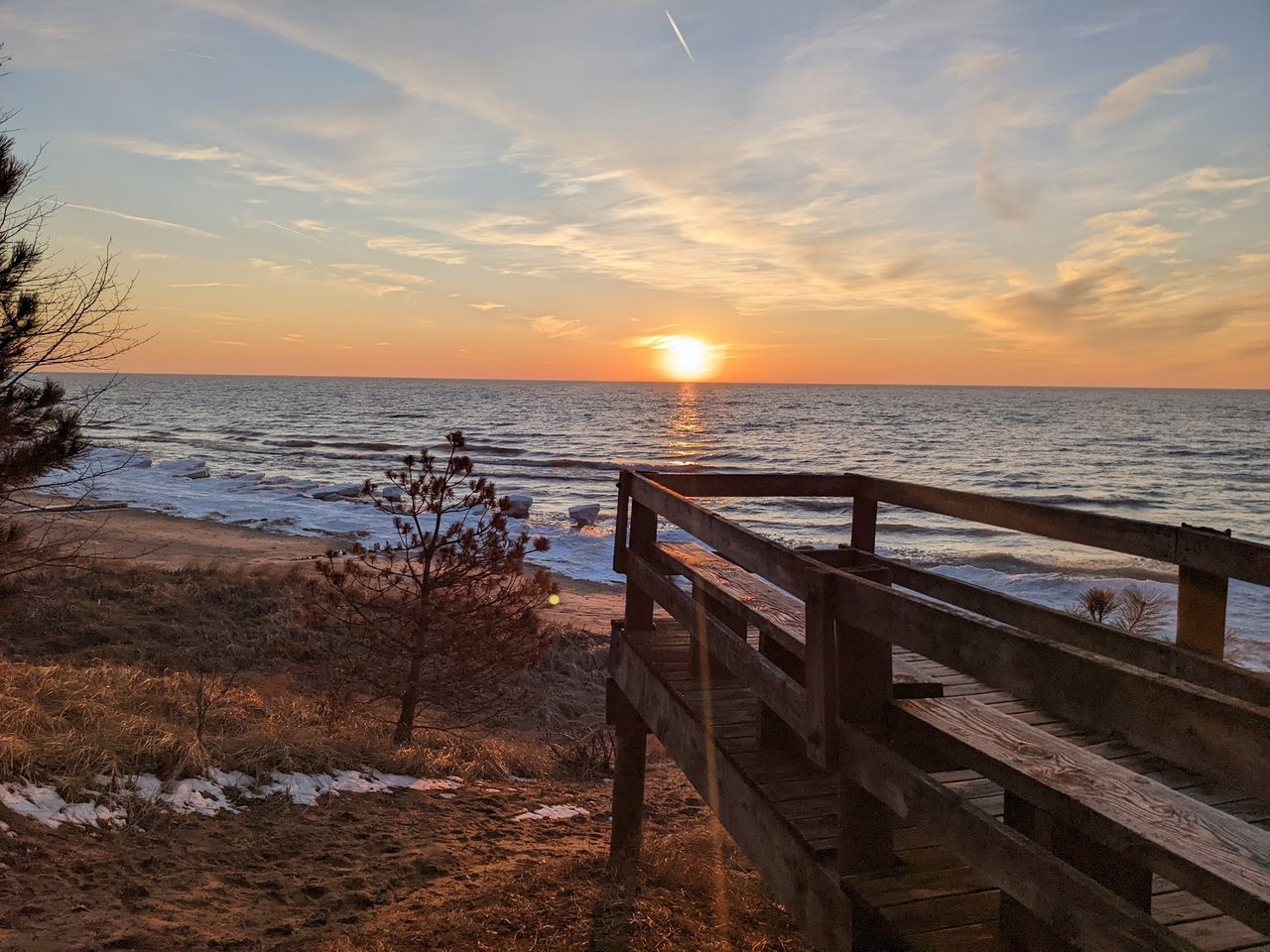 Sunset over Lake Michigan from Covert Township Beach with wooden overlook and sandy shoreline.