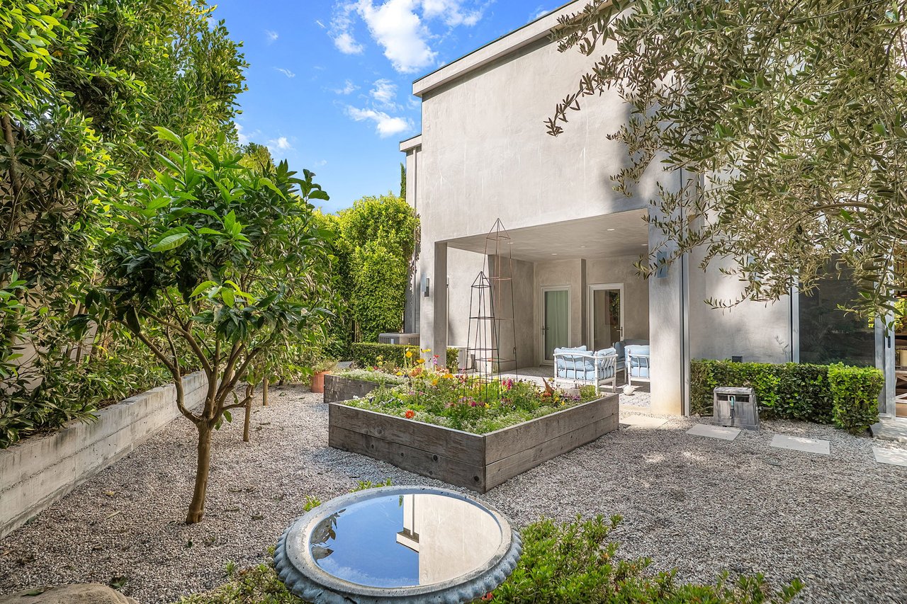 Modern home courtyard with raised flower beds, outdoor seating, and a circular reflecting pool.