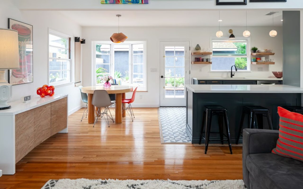 A brightly lit open-concept kitchen and dining area with a modern, colorful feel, featuring hardwood floors and an island.