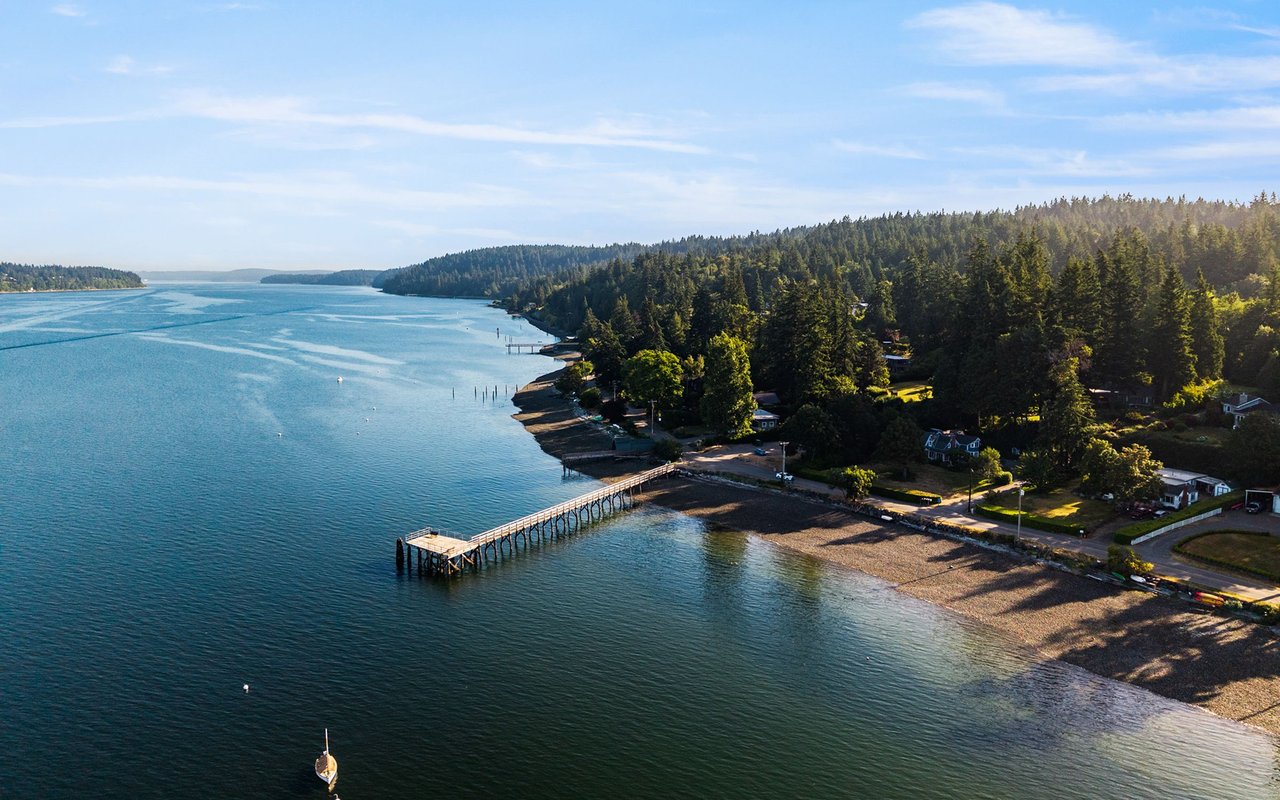 Point White shoreline with waterfront homes, a long pier, and calm blue water.
