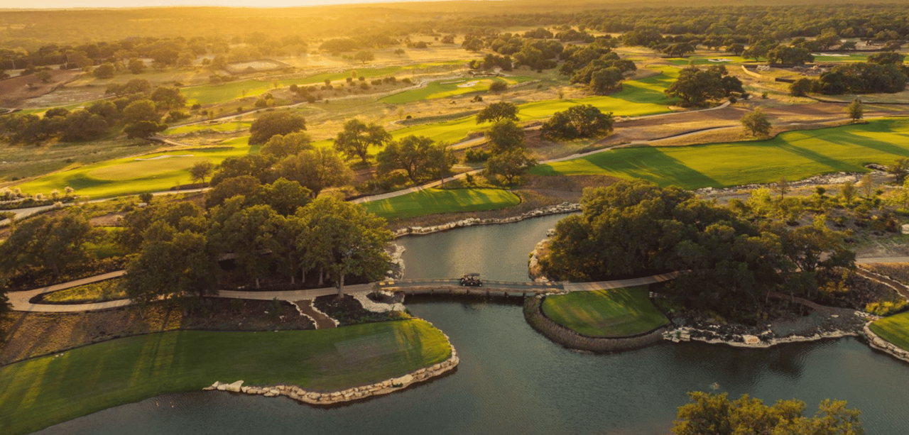 Aerial view of Driftwood Golf & Ranch Club fairways winding around a river and wooded hills.