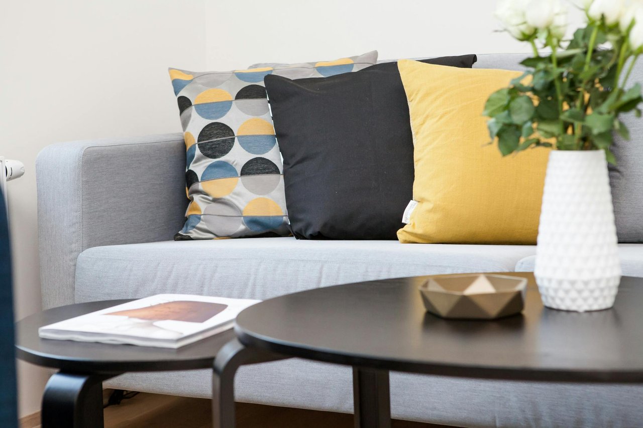 A grey couch adorned with vibrant yellow and black pillows, creating a stylish and modern living space.