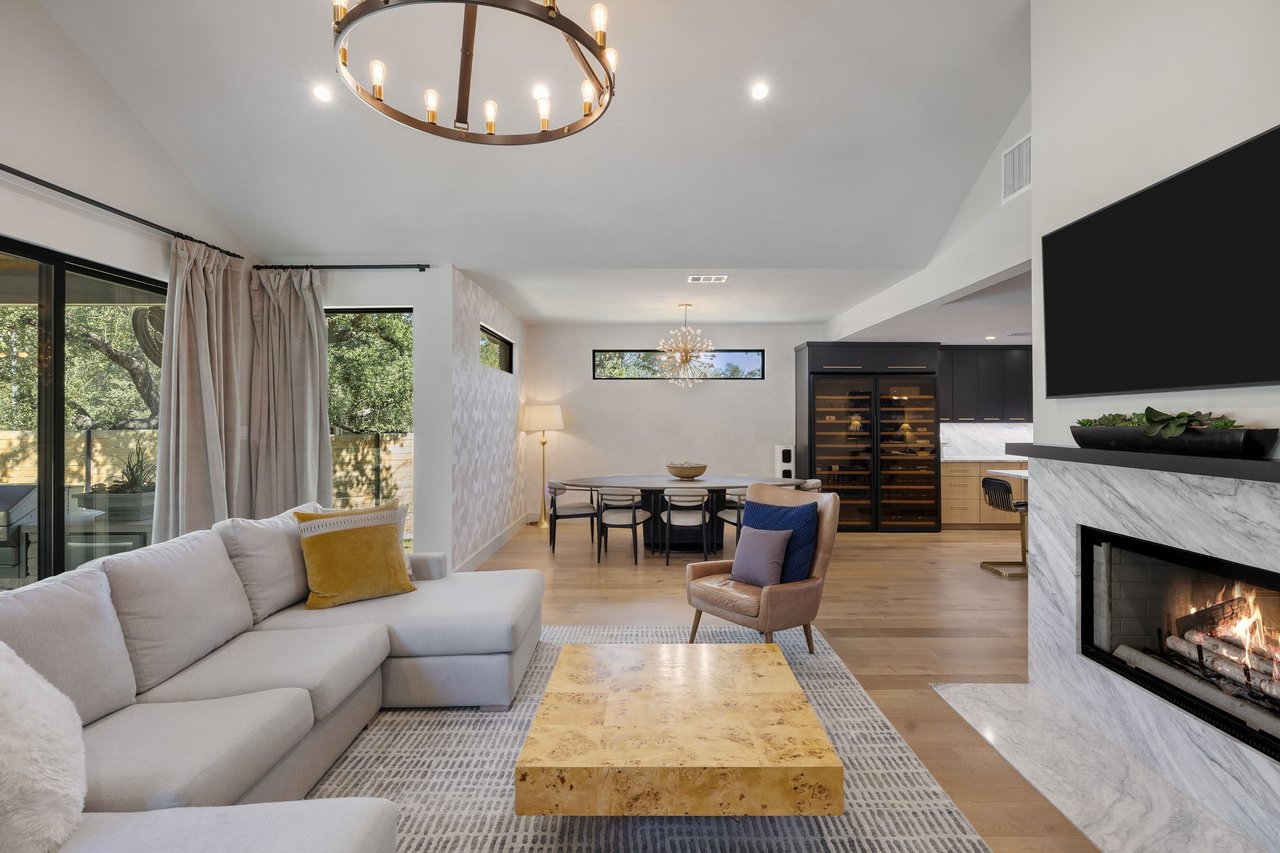 Open-plan living room with a marble fireplace, large sectional sofa, and dining area beyond.