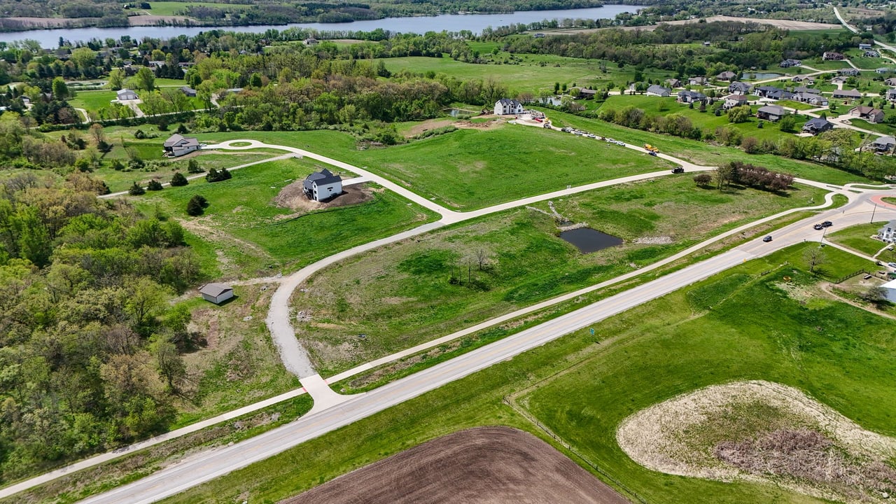 Oak Meadow development with open green lots, winding roads, scattered homes, and a river in the distance.