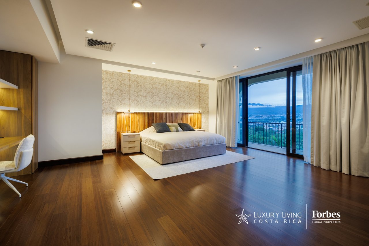 Penthouse bedroom with a king-size bed and balcony doors overlooking the city and mountains.