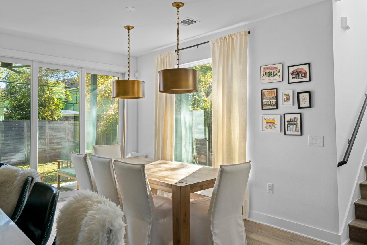 Dining room at 404 Powell Cir Unit B in Austin's Dawson neighborhood, with a wood table, brass drum pendant lights, and a gallery wall of framed art.