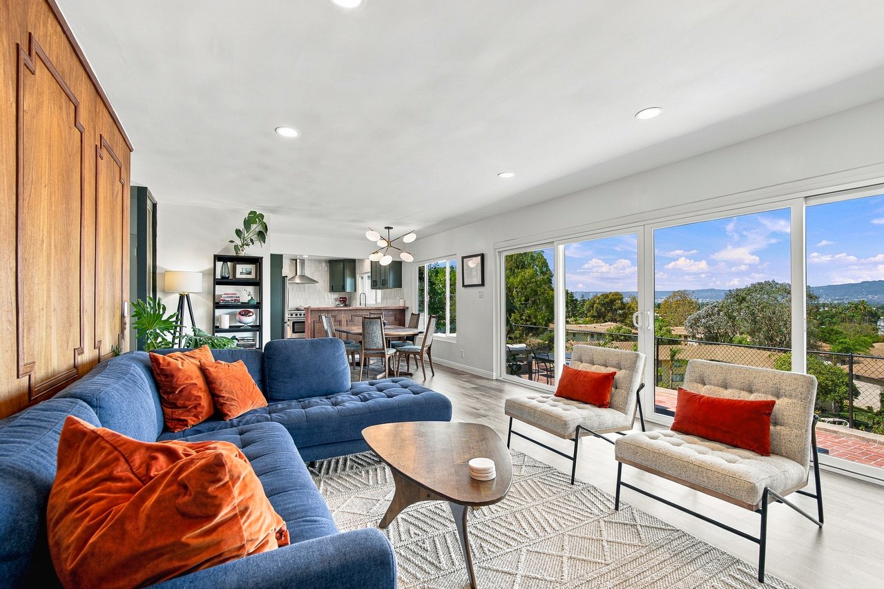 Open-plan living room with blue sofa and expansive Los Angeles views through sliding glass doors