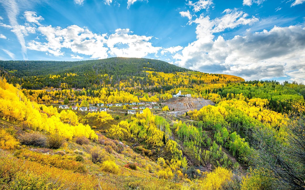 Stone patio fire pit overlooking Aspen’s glowing valley and forested mountains at dusk.