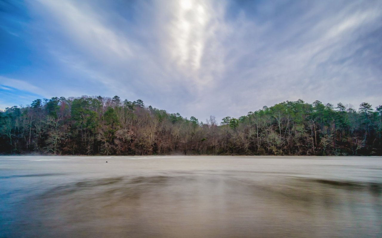 A long exposure of a lake with trees in the background