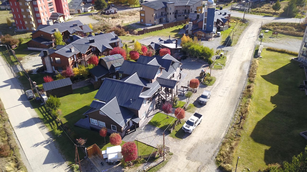 Aerial view of chalet-style homes beside a gravel road.