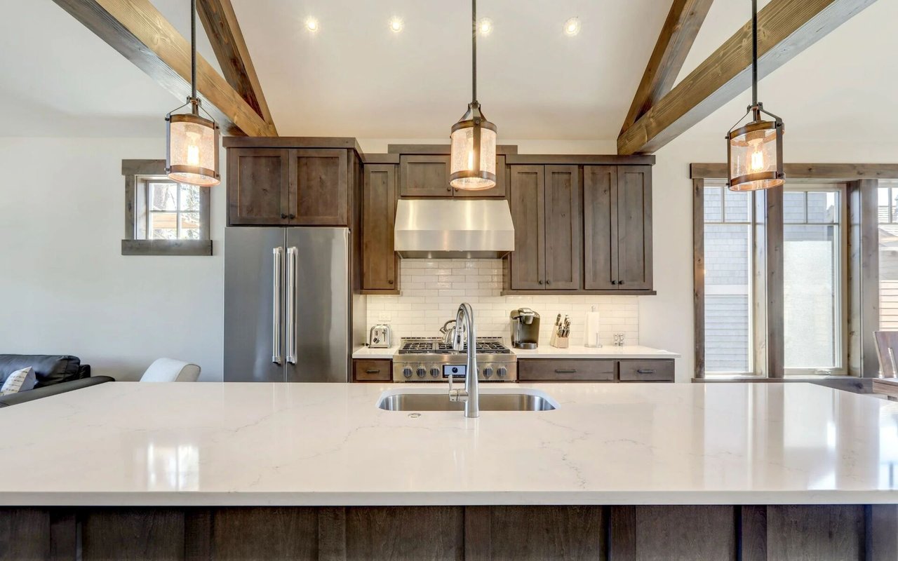 Kitchen with dark wood cabinetry, exposed beams, and a large white island with sink.