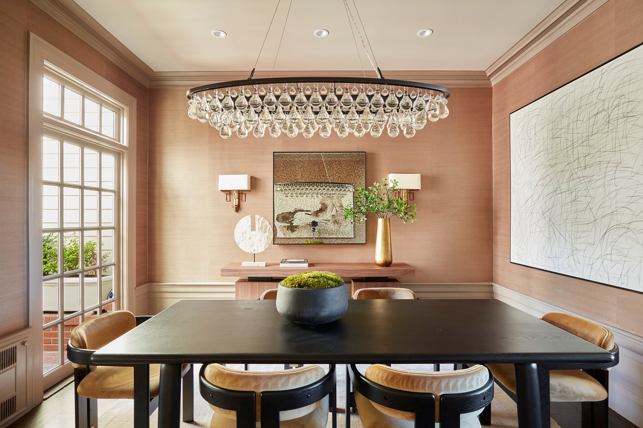 Dining room with a long dark table, upholstered chairs, and a crystal chandelier.