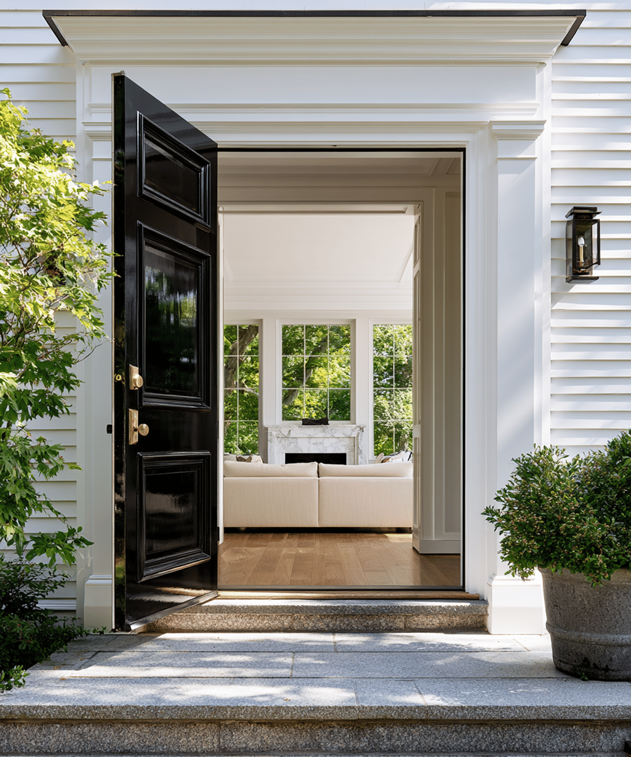 Open black front door reveals a bright living room with a white sofa and marble fireplace.