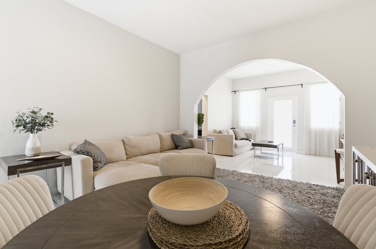 Furnished living room with a cream sectional and a wide arch opening to a second sitting area.