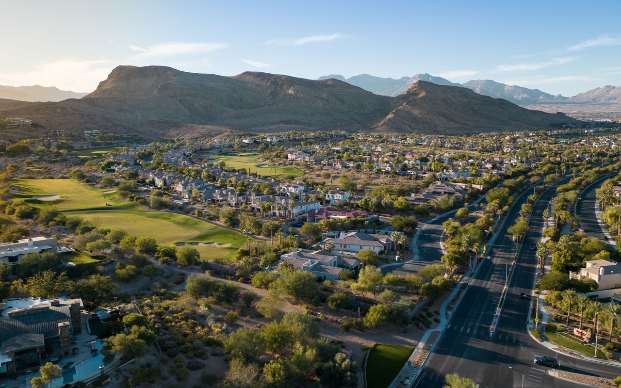 Aerial view of Somersett homes and golf course beneath rugged mountains.
