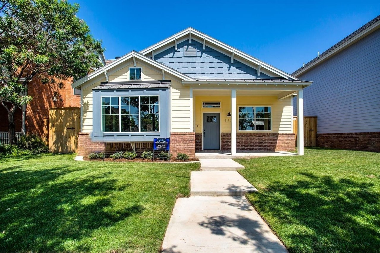 Single-story home with a blue gabled roof, covered entry, brick base, and front lawn.