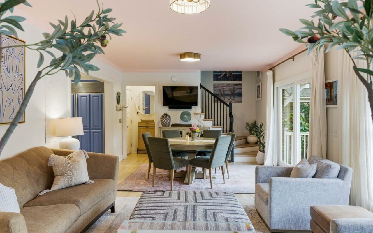 Staged living and dining room with a round table, blue cabinetry, and large windows.