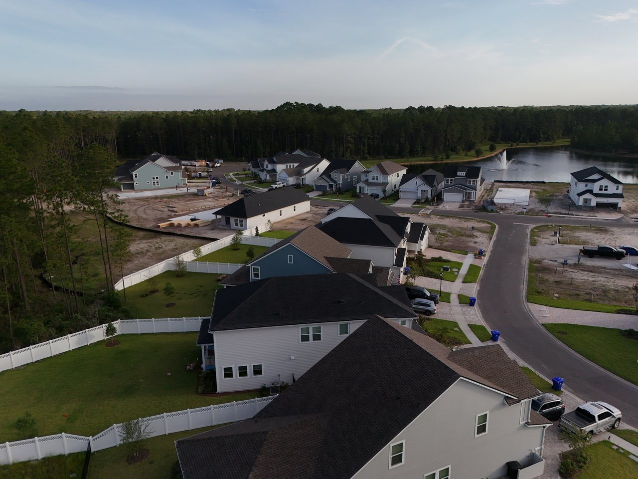 Aerial view of homes and construction lots beside a pond with a fountain.