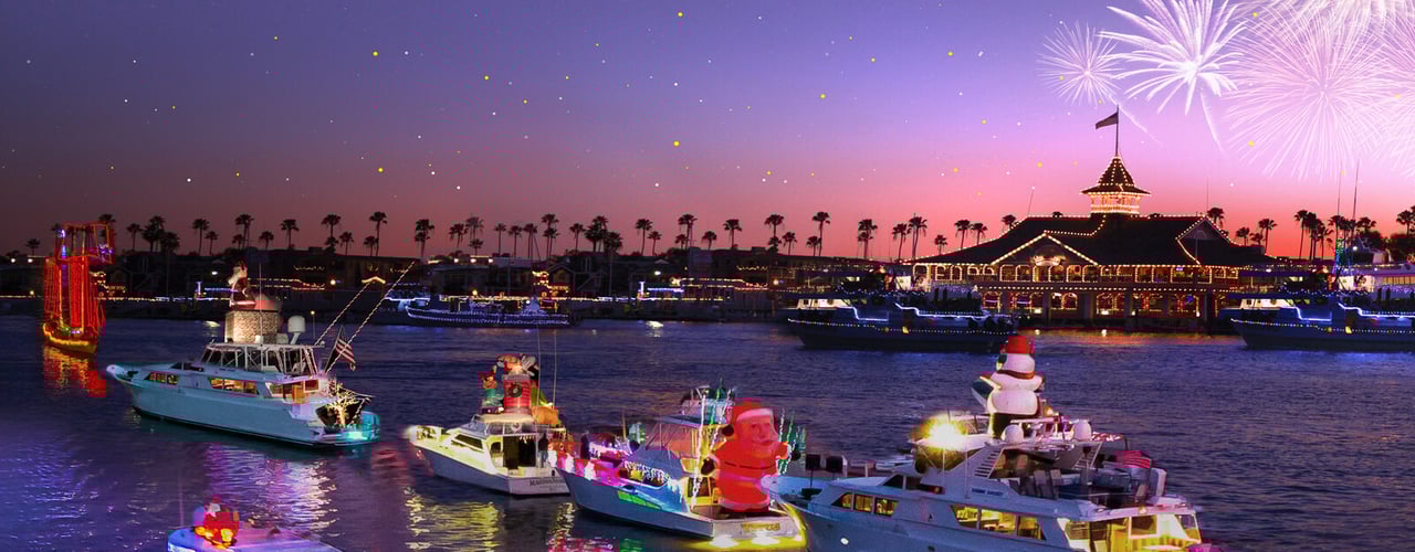 Colorful holiday lights reflecting on the water along the Newport Beach Peninsula at night