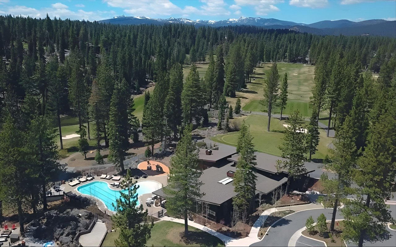 Schaffer’s Mill clubhouse and pool beside a golf course, surrounded by forest and mountain peaks.