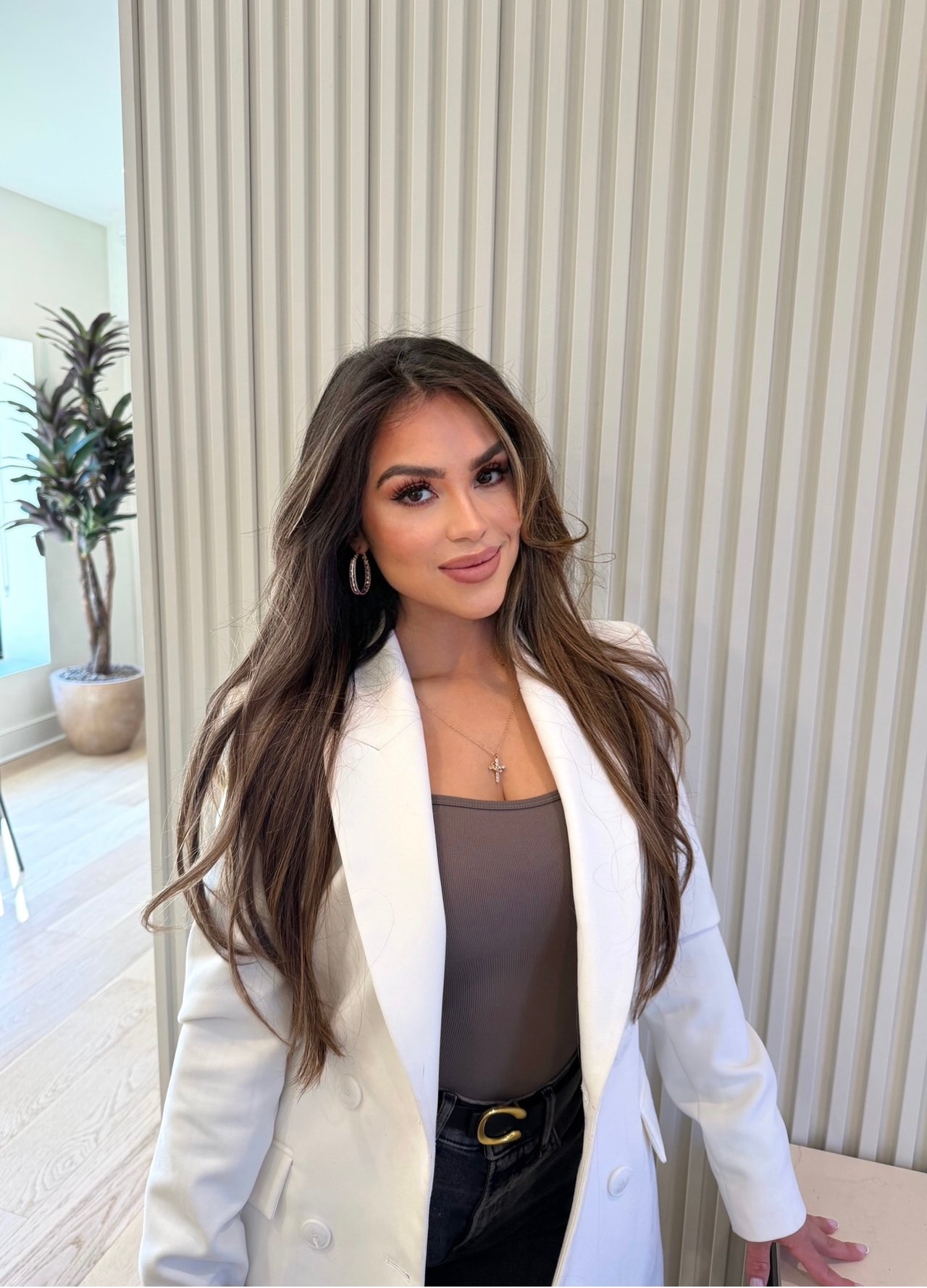 Karla Burga wearing a white blazer in a bright interior.