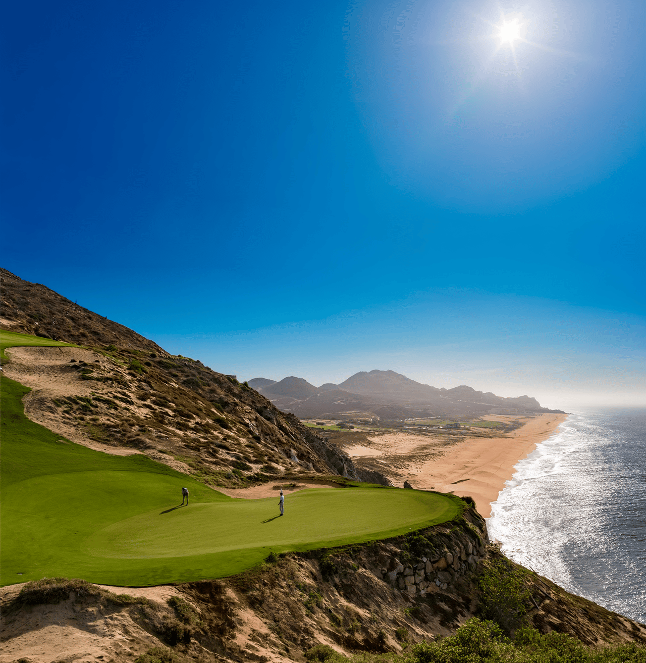 Golfers on an oceanfront green at Quivira Golf Club above the beach in Cabo San Lucas
