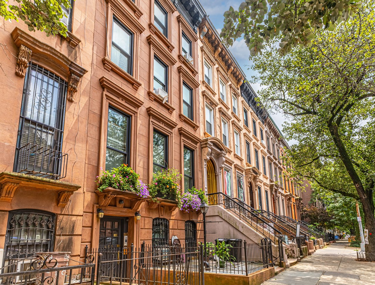 Row of historic Bed-Stuy brownstone townhouses with stoops and tree-lined street, presented by The Parviz Team at Compass.