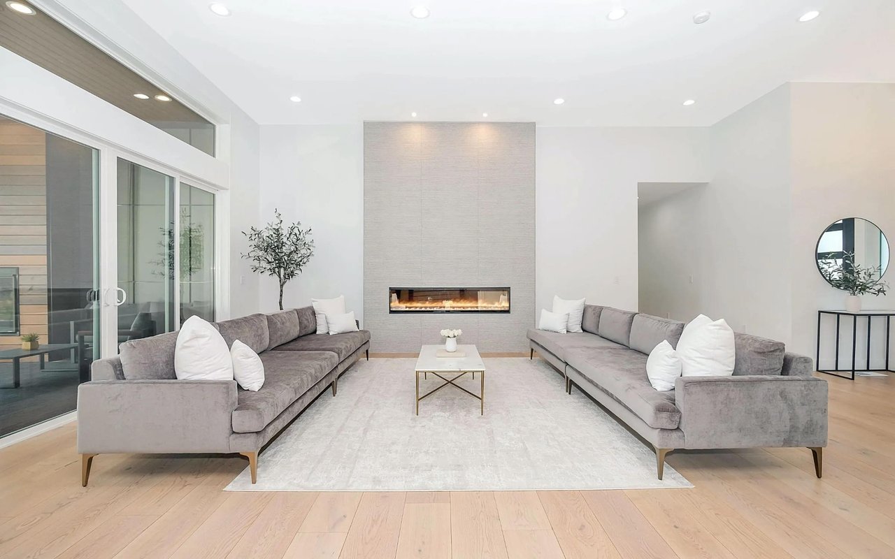 Modern living room with paired gray sofas, a linear fireplace, and large sliding glass doors.