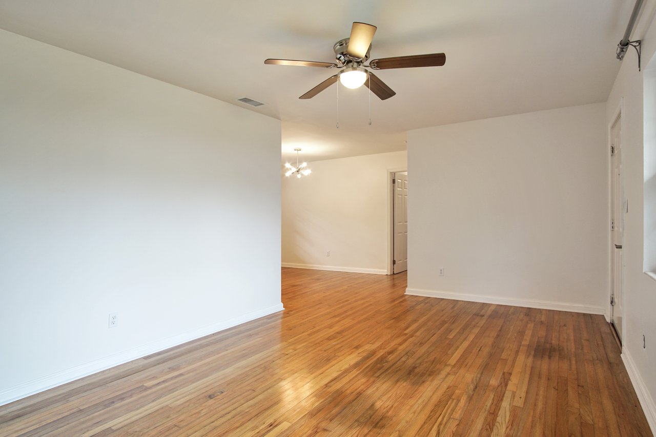 An empty utility storage room featuring hardwood floors and a ceiling fan, providing a spacious and airy atmosphere.