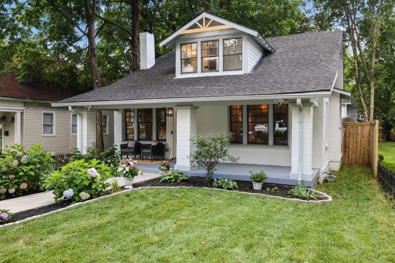 White house with a large roof dormer, covered porch, and landscaped front garden.