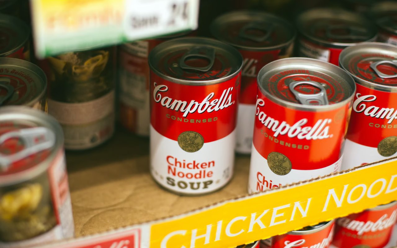 A close-up, eye-level shot of multiple cans on a shelf in a grocery store.