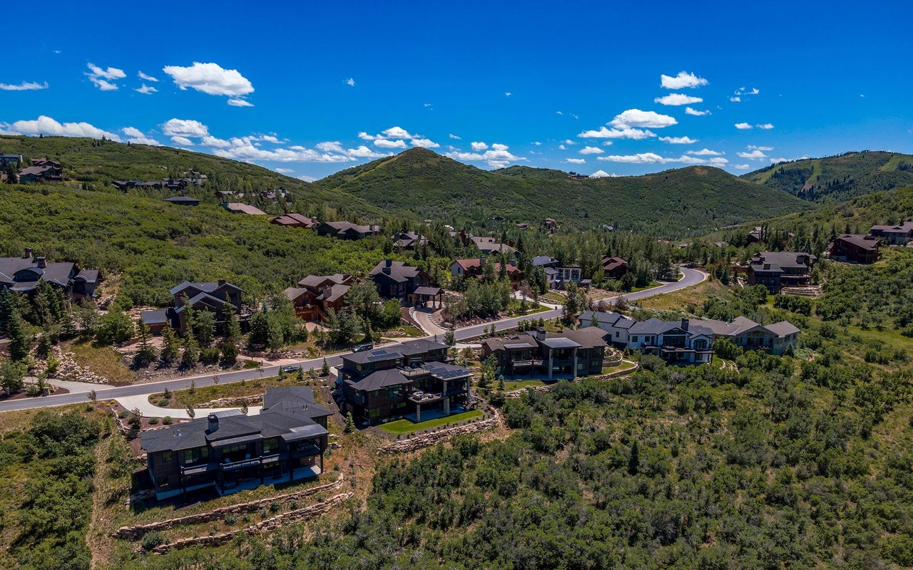 Aerial view of homes along a winding road among Pinebrook’s green hills and mountain ridges.