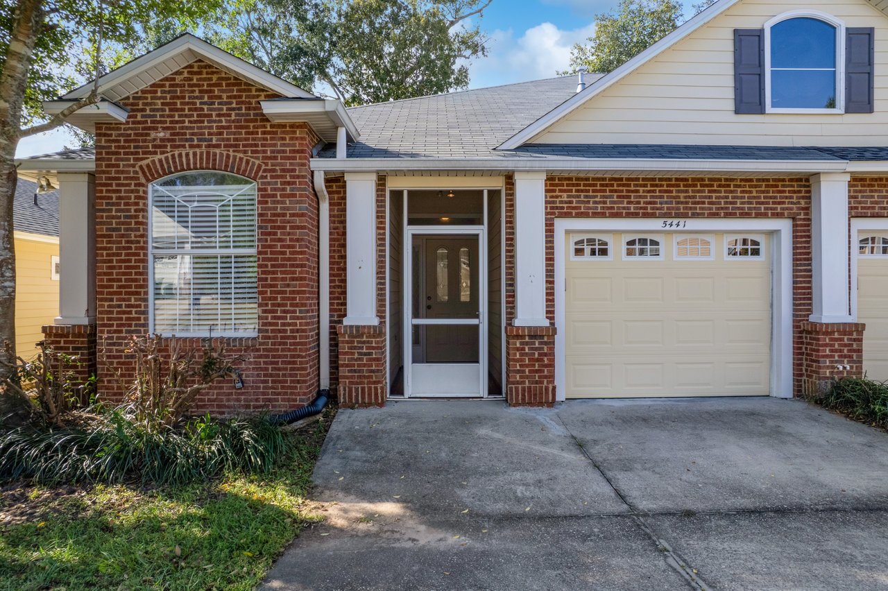 Front entry of 5441 Hampton Hill Circle, Tallahassee, Florida 32311 showing brick exterior, white columns, and single-car garage.