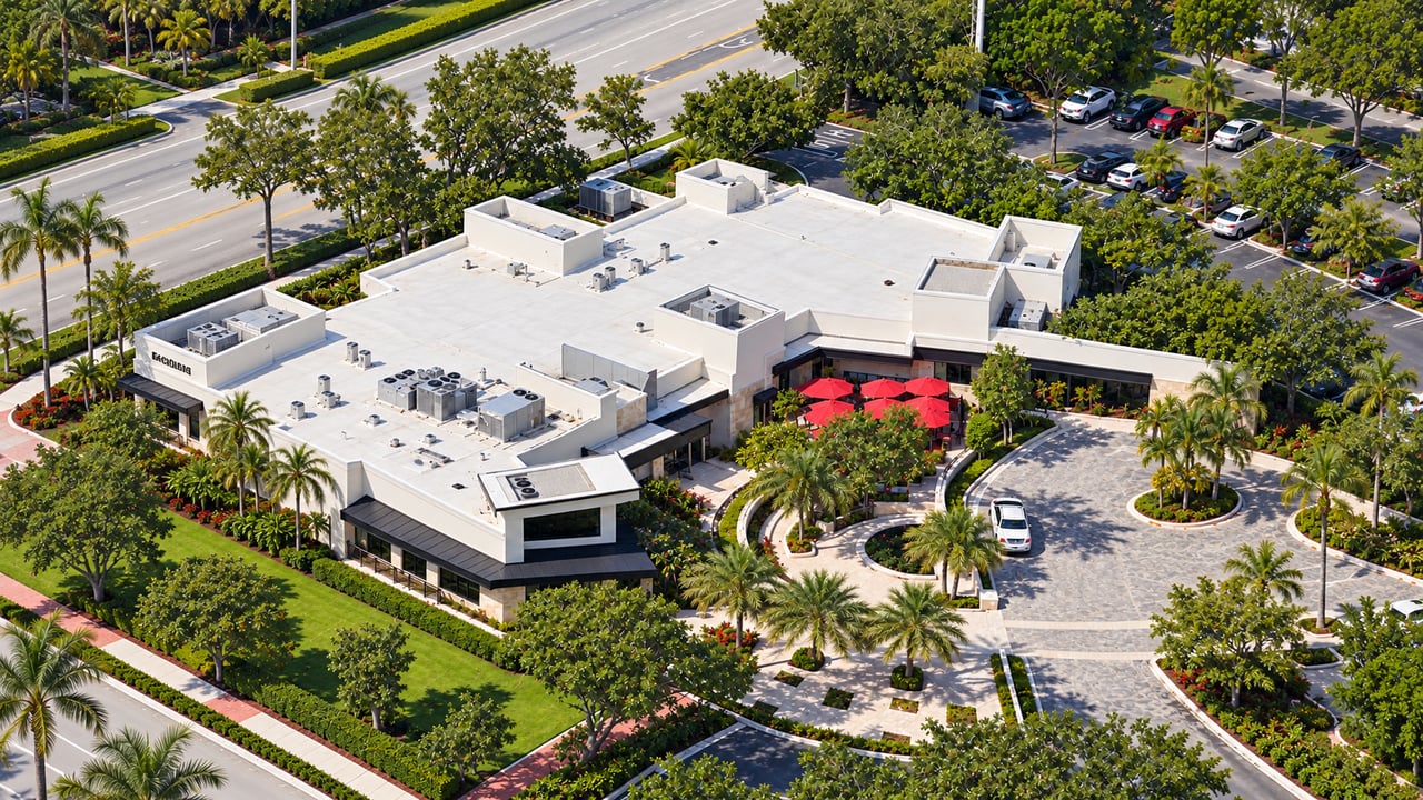Aerial view of a low-rise commercial building with palm-lined grounds and a circular front drive.