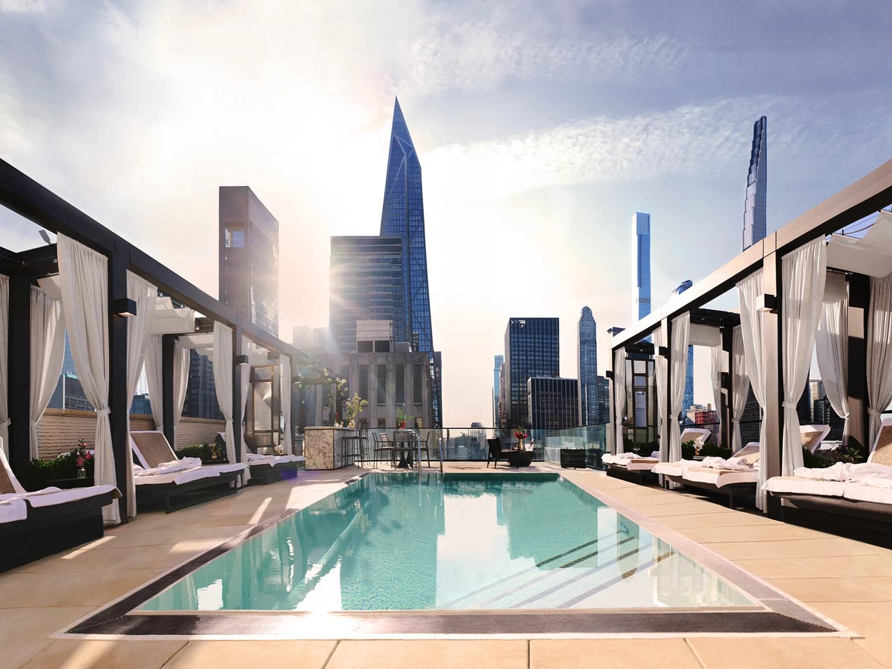 Rooftop pool with curtained cabanas overlooking the Manhattan skyline.