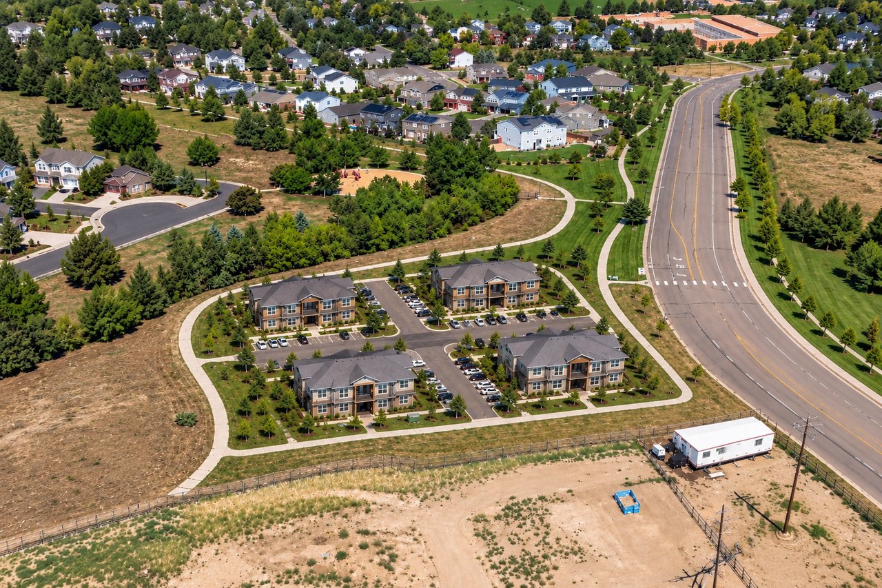 Aerial view of homes and low-rise apartment buildings beside a wide road.