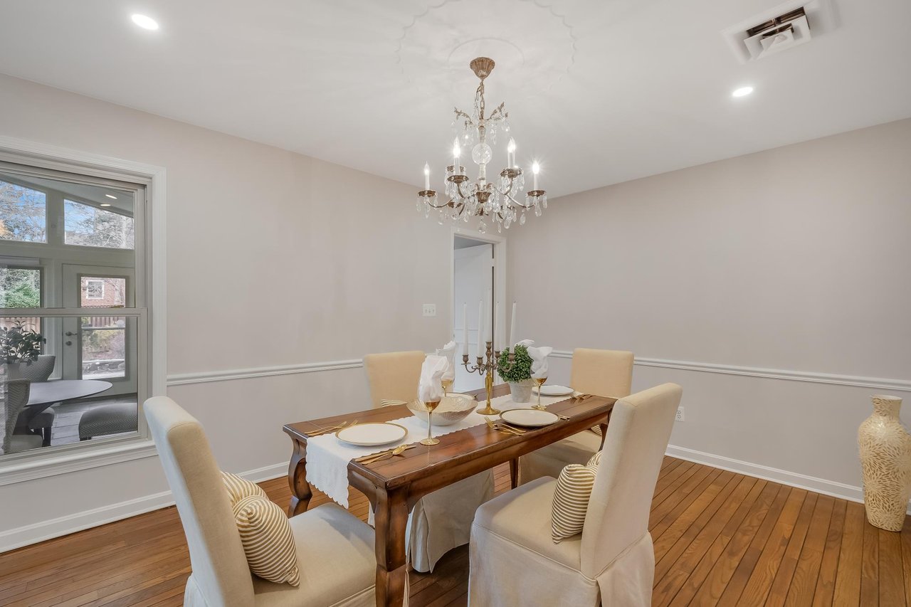 Dining room with a set wooden table, cream chairs, and a crystal chandelier.